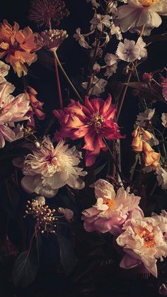 a bunch of flowers that are sitting in a vase on a table with dark background