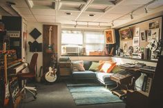 a living room filled with lots of furniture and musical equipment on the wall next to a window