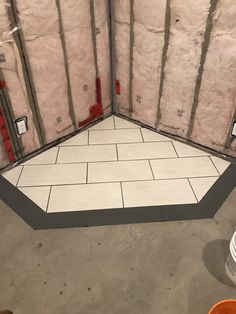 an unfinished room with white tile and red piping