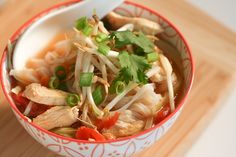 a red and white bowl filled with food on top of a wooden table