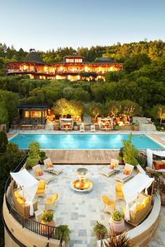 an aerial view of a pool and patio area at dusk with lounge chairs around it