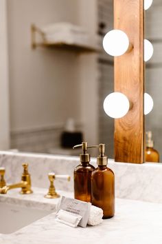 a bathroom sink with soap dispenser and lighted mirror in the back ground