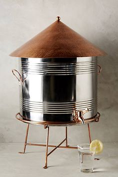 a large metal pot sitting on top of a table next to a glass filled with water