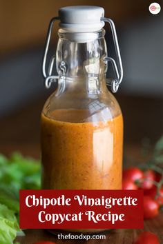 a glass jar filled with chipotle vinaigrete copyecat recipe next to lettuce and tomatoes