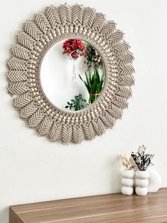 a mirror that is on the wall above a table with flowers and vases in front of it