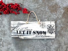 a sign that says let it snow hanging on a wall next to some red berries