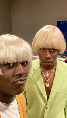 two men wearing wigs and one is looking at the camera