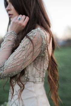 a woman with long hair wearing a white dress and holding her hand to her ear