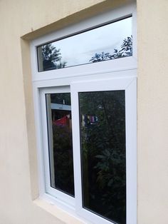 a cat sitting on the ledge of a window sill looking out at trees outside