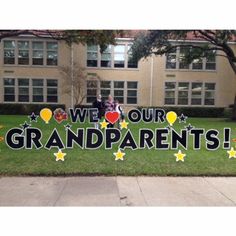 two people standing in front of a sign that says we love our grandparents