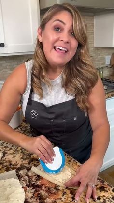 a woman in an apron preparing food on a kitchen counter top with a blue and white spatula