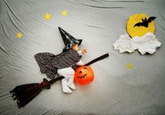 a baby dressed up as a witch laying on top of a bed next to two pumpkins