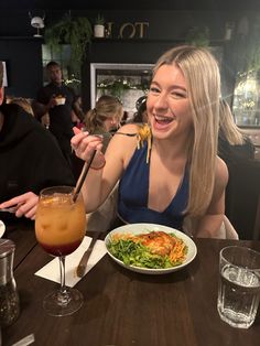 a woman sitting at a table with a plate of food and drink in front of her