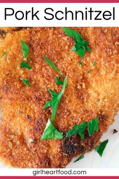 two pieces of fried chicken on a white plate with parsley sprig garnish