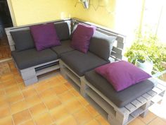 a couch made out of pallets with purple and grey pillows sitting on top of it