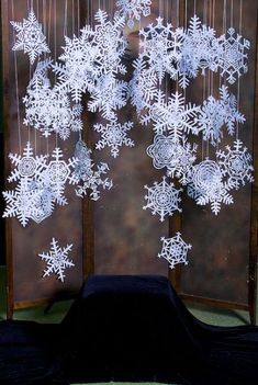 snowflakes are hanging on the wall in front of a black cloth covered table