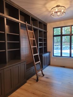 a ladder leaning against the wall in an empty room with built - in bookshelves