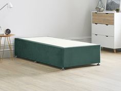 a bed sitting on top of a wooden floor next to a white wall