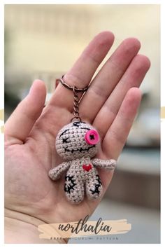 a hand holding a tiny crocheted keychain with a pink heart on it