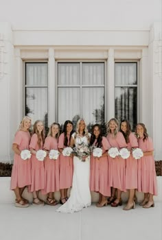 a group of women standing next to each other in front of a white building with windows