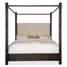 a bed that has a white blanket and pillows on it, with a wooden frame around the headboard