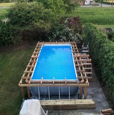 an above ground swimming pool in the middle of a yard with wood framing around it