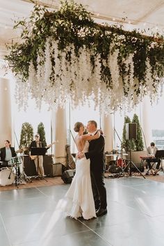 a bride and groom sharing their first dance in front of the wedding band on stage