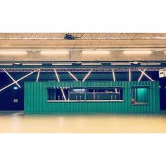 an empty room with green shipping containers on the floor and lights hanging from the ceiling