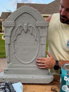 a man is working on a cement monument with paint and a can of water next to it