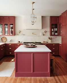 a kitchen with red cabinets and white counter tops