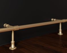 a close up of a metal rail on a wooden floor with black walls in the background