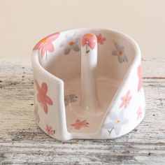 a flowered bowl with two spoons in it sitting on a table next to a wall