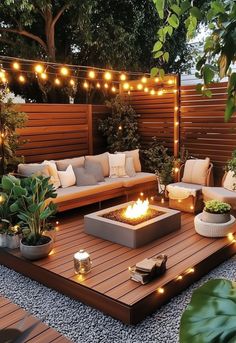 an outdoor living area with lights strung over the fire pit and seating for people to sit on