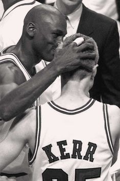 two basketball players giving each other a big piece of food in front of their faces