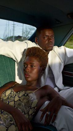 two people sitting in the back seat of a car, one is wearing a white coat