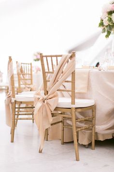 chairs with bows tied to them are set up for a formal function at a wedding