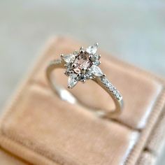 an engagement ring is sitting on top of a velvet box, with the diamond set in it's center