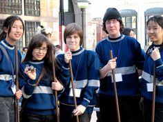 four young people wearing blue sweaters and holding canes