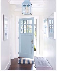 a blue front door with a bench in the hallway next to it and a light fixture hanging from the ceiling