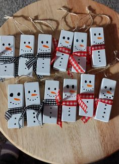 snowmen made out of dominos sitting on top of a wooden table next to string