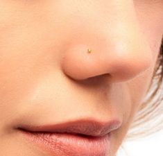 a woman's nose is shown with gold piercings on her left side and right side