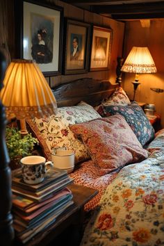 a bed covered in lots of pillows next to a table with a lamp on it