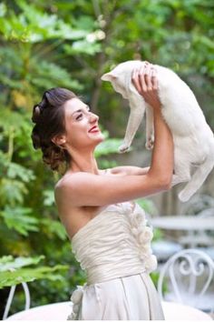 a woman in a wedding dress holding a white cat