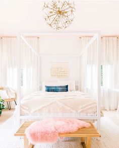 a white canopy bed sitting in a bedroom next to a pink rug on the floor