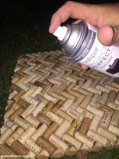 a hand is holding a spray bottle over some wine corks