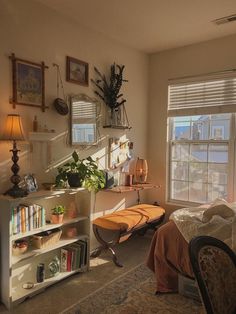 a bedroom with a bed, bookshelf and various plants in the window sill