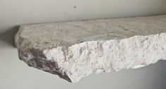 a close up of a stone shelf on a wall in a room with white walls