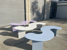 three different colored benches sitting on the side of a road next to a garage door