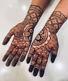 two hands with henna tattoos on them, one is showing the intricate design and the other has flowers