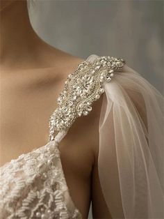 the back of a woman's wedding dress, with an elaborate beaded shoulder